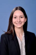woman with dark brown hair in a blazer smiling