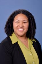 woman in a green top with short curly hair smiling
