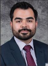 man in a suit with a dark beard smiling lightly