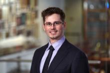man with short brown hair and glasses on smiling