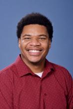 man in a red, polka dot polo smiling