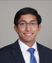 man with dark hair and glasses on smiling