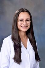 woman doctor with long brown hair and glasses smiling