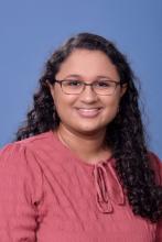 woman with long curly hair and glasses on smiling