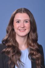 woman with long, curled brown hair smiling