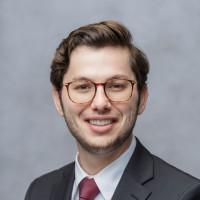 Gentleman with brown hair and glasses, wearing gray blazer and maroon tie