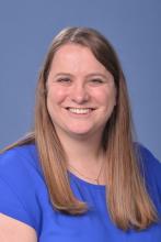 woman with dark blonde hair and a blue top on smiling