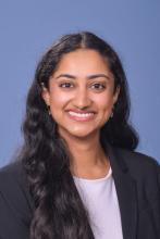 woman with long dark hair, in a blazer smiling