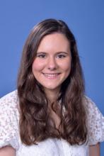 woman in a white top with brown hair smiling