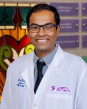 man with dark hair and glasses on smiling