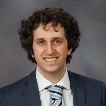 man with brown curly hair smiling