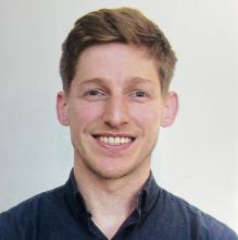 man with short, dark blonde hair smiling