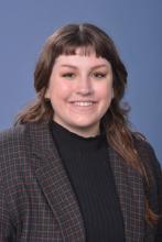 woman in a dark top and blazer with brown hair smiling