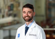 man with short brown hair and a beard, smiling