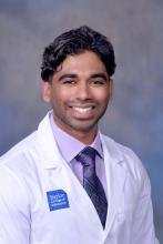 man with dark wavy hair smiling