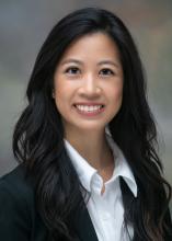 female with dark long hair, wearing dark blazer and white button up shirt