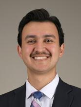 man with dark hair and a mustache smiling