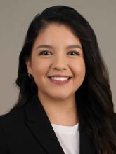 woman with long dark hair in a black blazer smiling