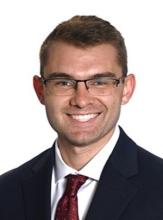 man with glasses on and short dark blonde hair smiling