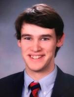 man with brown hair, in a suit smiling