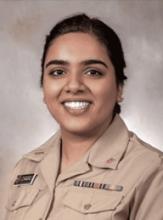 woman with dark hair in a low, tied-back hairstyle smiling