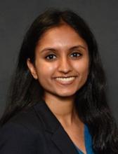 woman in a blazer and teal blouse smiling