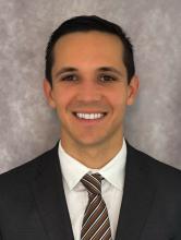 man smiling in front of a grey backdrop