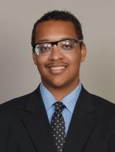 man in a suit with rectangle glasses on smiling