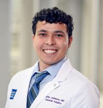 man with short, dark curly hair smiling