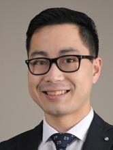 man with black hair and black glasses on smiling