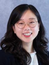 woman with dark, curled hair and glasses on smiling