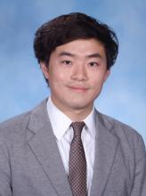 man in a grey suit with dark hair smiling lightly