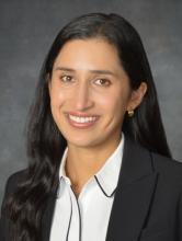 woman with dark hair in business attire smiling