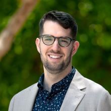 photo of man in a suit smiling outside