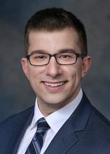 man with short hair and black glasses on smiling