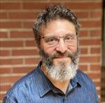 man smiling in front of brick background