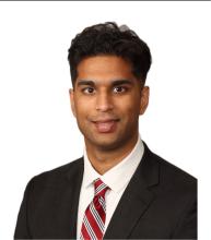 man with dark hair in a suit and tie smiling