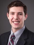 man with brown hair and a striped tie on smiling