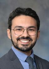 man with dark hair and glasses on smiling