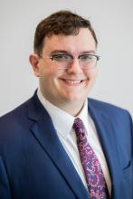 man with brown hair and glasses on smiling