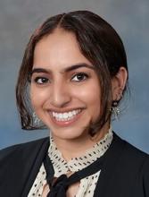 woman with her hair pulled back and a middle part smiling
