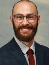 man with glasses on and a beard smiling