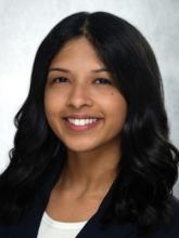 woman with long, curled dark hair smiling