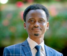 man smiling outside while wearing a blue sute