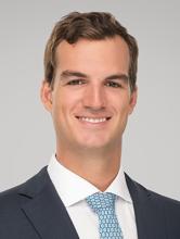 man with brown hair and in a dark grey suit smiling