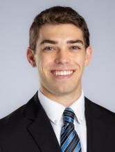 man with brown hair and a black suit on smiling