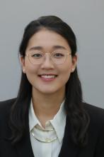 woman with dark hair and round glasses on smiling