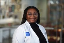 woman with dark hair positioned behind her shoulders, smiling