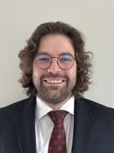 man with curly hair and glasses on smiling