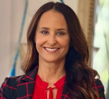 woman in a red blouse with long brown hair smiling